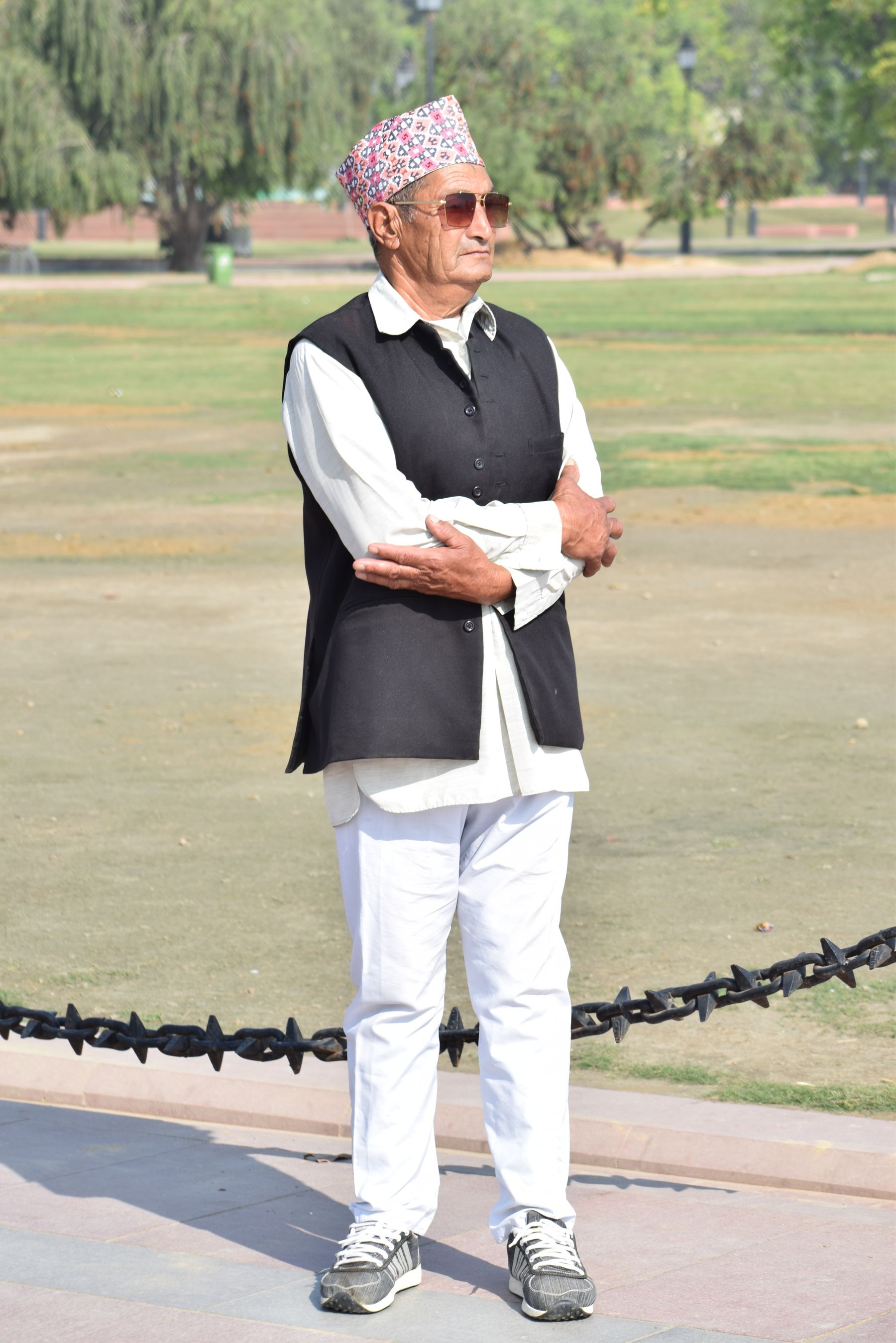 Illustrative photograph: A mature gentleman in a tailored waistcoat and traditional cap relaxing in a green park.