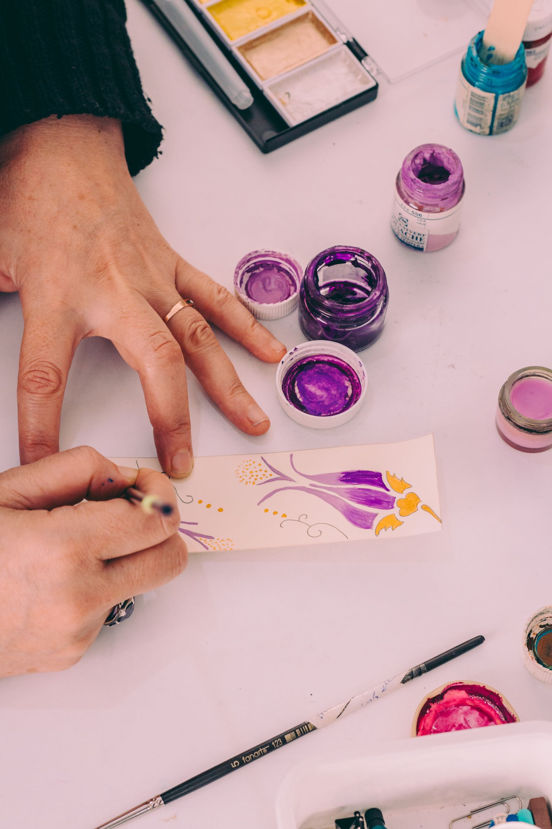 Illustrative photograph: An artist using a fine paintbrush to make a colourful floral watercolour.
