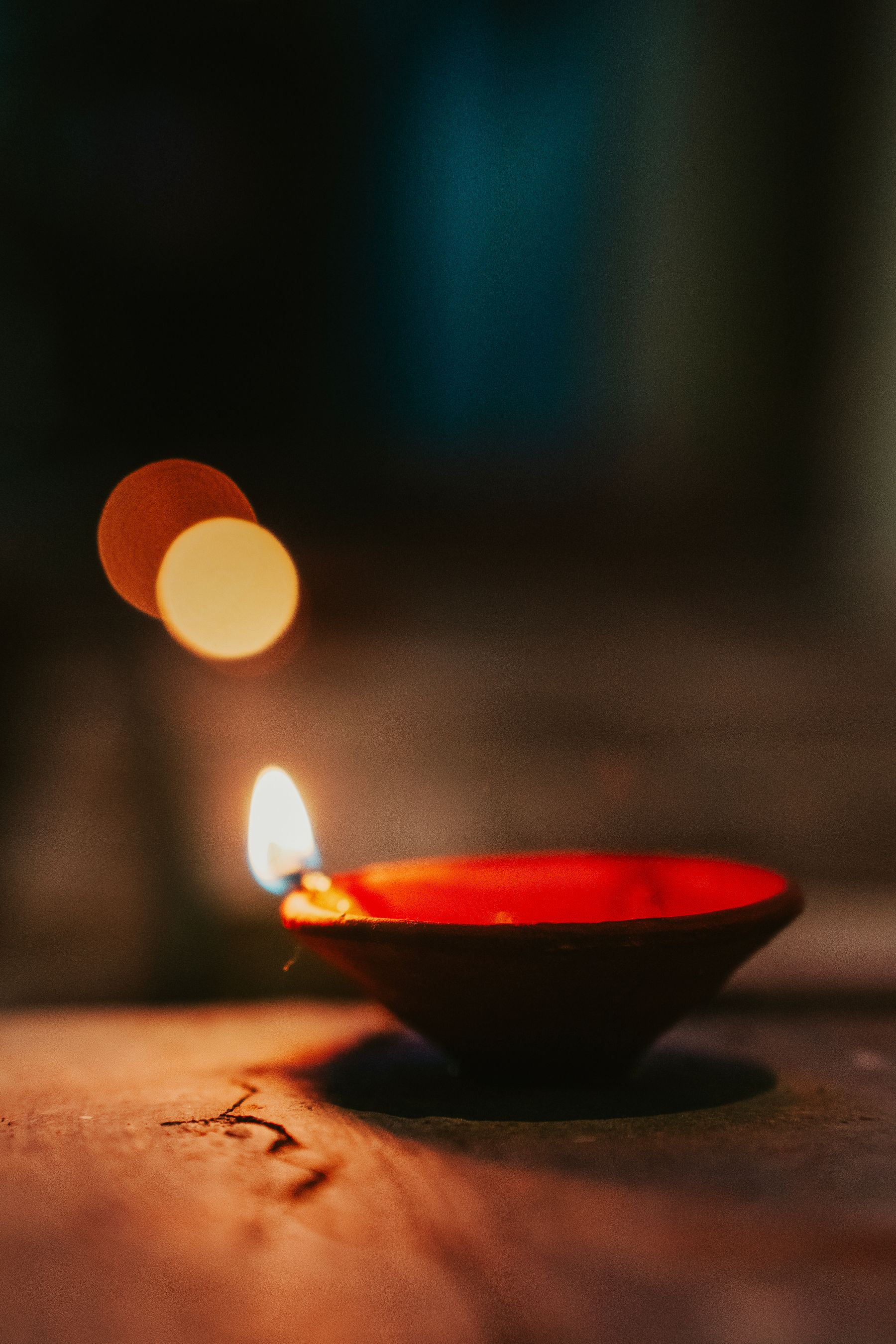 Illustrative photograph: A terracotta diya glowing in a softly lit festive setting.